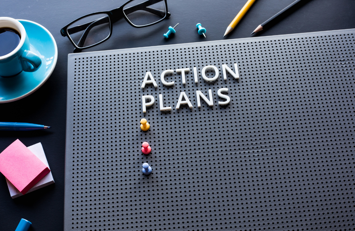 Workspace with an action plan board labeled ‘Action Plans,’ using pins and office tools to organize and track planned tasks.